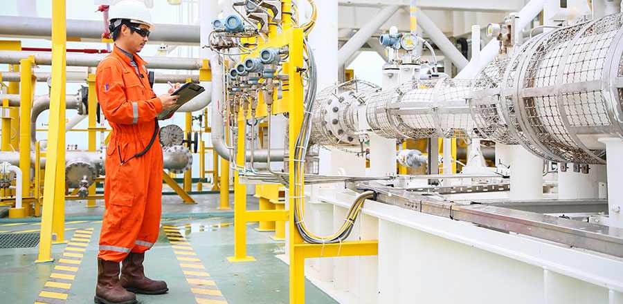 Operador em fábrica química monitorando sistema de alerta para situações de emergência